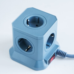 A blue cubic power strip featuring four euro sockets and an illuminated red switch, ideal for organizing and powering multiple home or office electronics without clutter. Photo