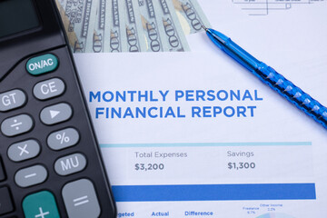 A monthly personal financial report with expenses and savings, alongside a calculator, pen, and dollar bills.
