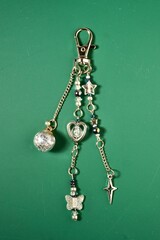 Silver gray beautiful bag charm decorative keychain isolated on vertical ratio green background.