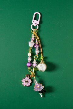 Beautiful flower beads and chain bag charm decorative keychain isolated on vertical ratio green background.