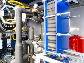 Plate heat exchanger system with insulated pipes, gauges, and valves in a modern industrial heating or cooling installation. Construction. Industrial equipment.