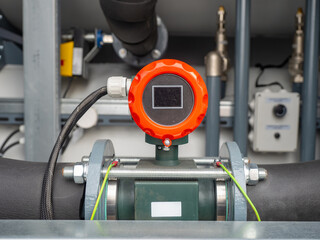Fototapeta premium Industrial electromagnetic flow meter installed on insulated piping system, used for monitoring fluid flow in process automation. Construction. Industrial equipment.