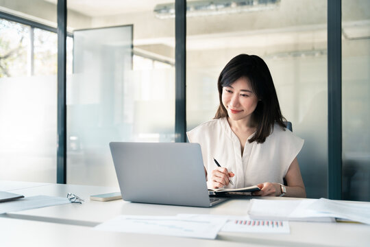 Middle-aged Asian woman using laptop computer for business studying, watch online virtual webinar training meeting, video call. Focused mature saleswoman businesswoman working in office, copy space.