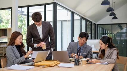 Group of diverse business professionals collaborating around a shared desk in a modern office setting.