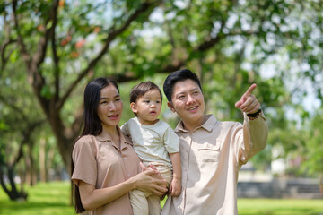 Happy Asian family walking together in a green park on a sunny day.