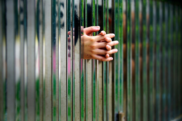 Obraz premium Hands Grasping Metal Bars in Enclosed Space with Reflection Effects
