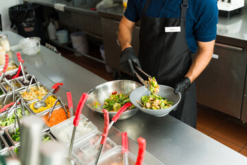 Cook preparing a fresh salad at salad bar restaurant