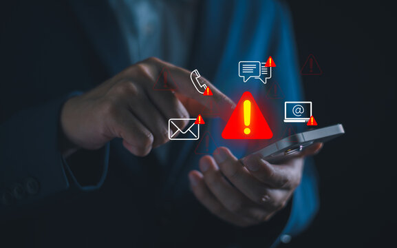 Businessman using smartphone with system warning alerts, Concept of cyber threat, phishing, scam messages, suspicious calls, and online security risks on mobile communication.