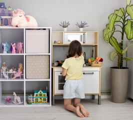 A child plays with a toy kitchen. A little girl plays in the children's room. The concept of leisure for children