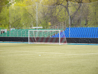 A soccer field with a white goal and blue seats