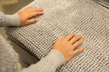 Woman checking quality shopping to buy. Female choosing new carpets at retail furniture store. Customer chooses hands touching and testing quality of product for her living room.