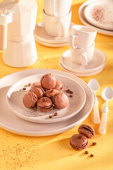 Fresh and tasty coffee macarons on plate on yellow background.