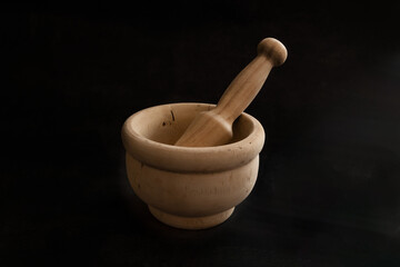 Traditional wooden mortar and pestle for grinding spices or herbs, rustic kitchen utensil, isolated on dark background. Ideal for cooking and culinary themes.