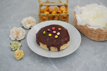 Delicious chocolate glazed donut with colorful sprinkles on a white plate