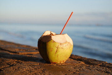 Coconut drink on the beach with a straw