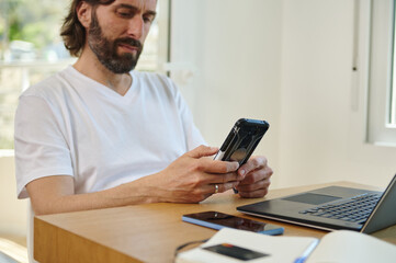 Relaxed Bearded Young Man Working Remotely in Minimalist Home Office