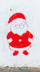 An adorable festive cartoon of Santa Claus is painted with red and white paint on the aged wall, evokes warmth and joy.