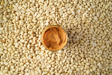 Jar of peanut butter on peanut background, flat lay composition, top view.