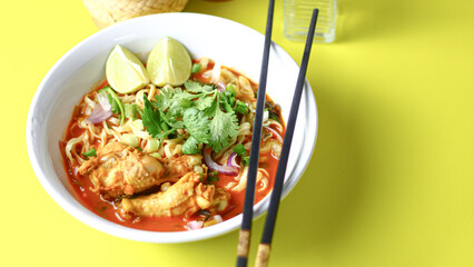A delicious Thai dish, khao soi, featuring spicy noodle soup with chicken, vibrant veggies, and aromatic spices, served with fresh cilantro and lime.