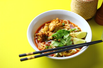 A delicious Thai dish, khao soi, featuring spicy noodle soup with chicken, vibrant veggies, and aromatic spices, served with fresh cilantro and lime.