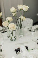 closeup of White roses in clear vases wedding table centerpieces
