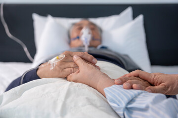 scene of family holding hands dying senior patient that having oxygen and iv drip on bed,concept of...