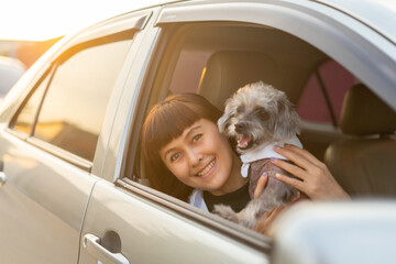 Young asian woman in casual outfit of cheerful with dog looking out of car window. Young female...