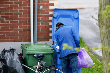 Un homme cherche des bouteilles vides dans les poubelles. Pauvreté urbaine.	