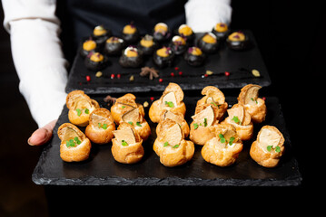 Elegant canapés served on black slate tray.