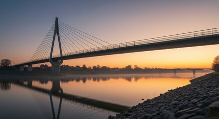 Obraz premium Sunrise over a modern cable-stayed bridge reflecting in the calm water