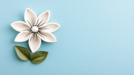 Naklejka premium A white ceramic flower with green leaves is arranged on a light blue textured background, creating a minimalistic and artistic design.