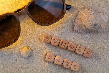 Summer 2025 beach vibes with sunglasses and seashells on sandy background