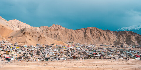 Panoramic view of Leh city in Ladakh, India, nestled in Himalayan mountains, dramatic brown ridges, peaceful townscape, rich Tibetan cultural influence