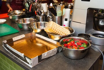 Pastry preparation setup with strawberries and ladyfingers.