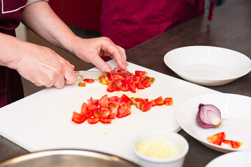 Chopping fresh tomatoes on cutting board.