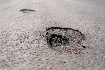 Potholes are visible on a city street, highlighting the urgent need for road repairs to ensure safety for vehicles and pedestrians