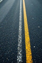 Fototapeta premium Asphalt Road Surface with White and Yellow Center Lines, Showing Texture and Detail