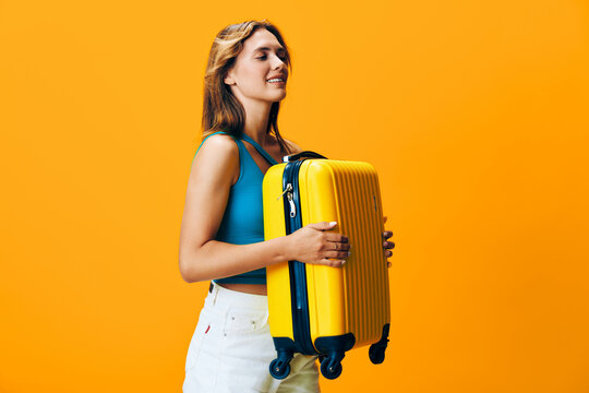 The joyous adventure awaits woman holding yellow suitcase smiling against vibrant orange backdrop