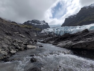 Fototapeta premium Low-angle view of Melting glacier forming a stream through a rocky valley.