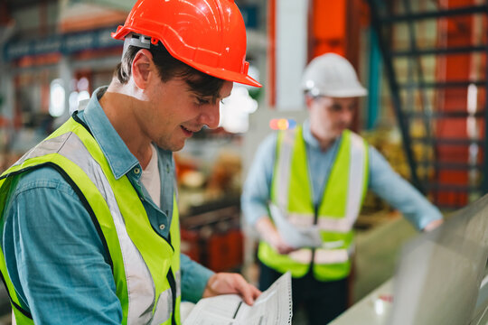 Engineers in high-visibility vests inspecting industrial control systems in modern factory, ensuring automation robotics, intelligent operations run under safety protocols, technical supervision