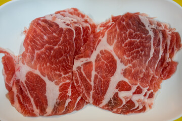 Fresh raw pork slice serving on the plate ingredient in hot pot restaurant.