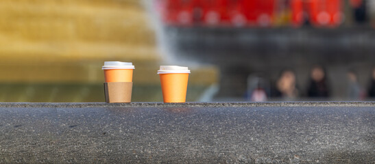 Two Takeaway Coffee Cups on Stone Ledge in Urban Setting