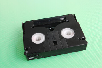 small black analog video cassette on a soft green background