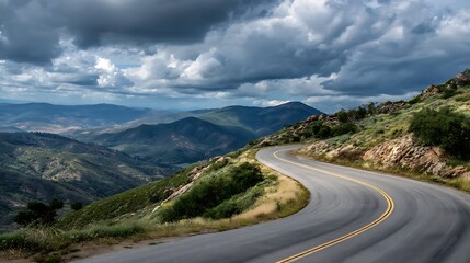 Naklejka premium Winding mountain road under a dramatic cloudy sky, scenic landscape photography