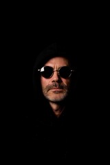 Obraz premium Man in hoodie and sunglasses looking to the side.
