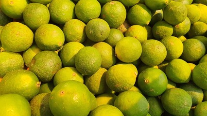 Close up pile of tasty fresh limes sold at the market as a background.