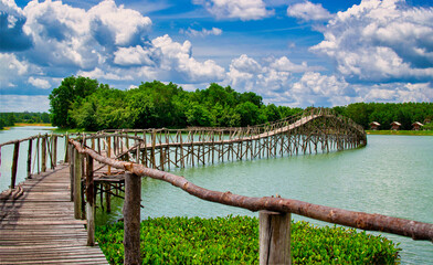 Old wooden bridge through river on blue sky background.