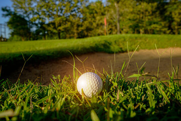 Golf ball is on a green lawn in a beautiful golf course with morning sunshine.