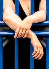 Naklejka premium A young woman is resting her arms on a fence.