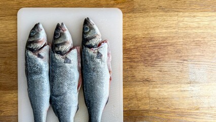 Three silvery fish resting in eerie alignment evoke Lunar New Year feasts, invoking tales of...